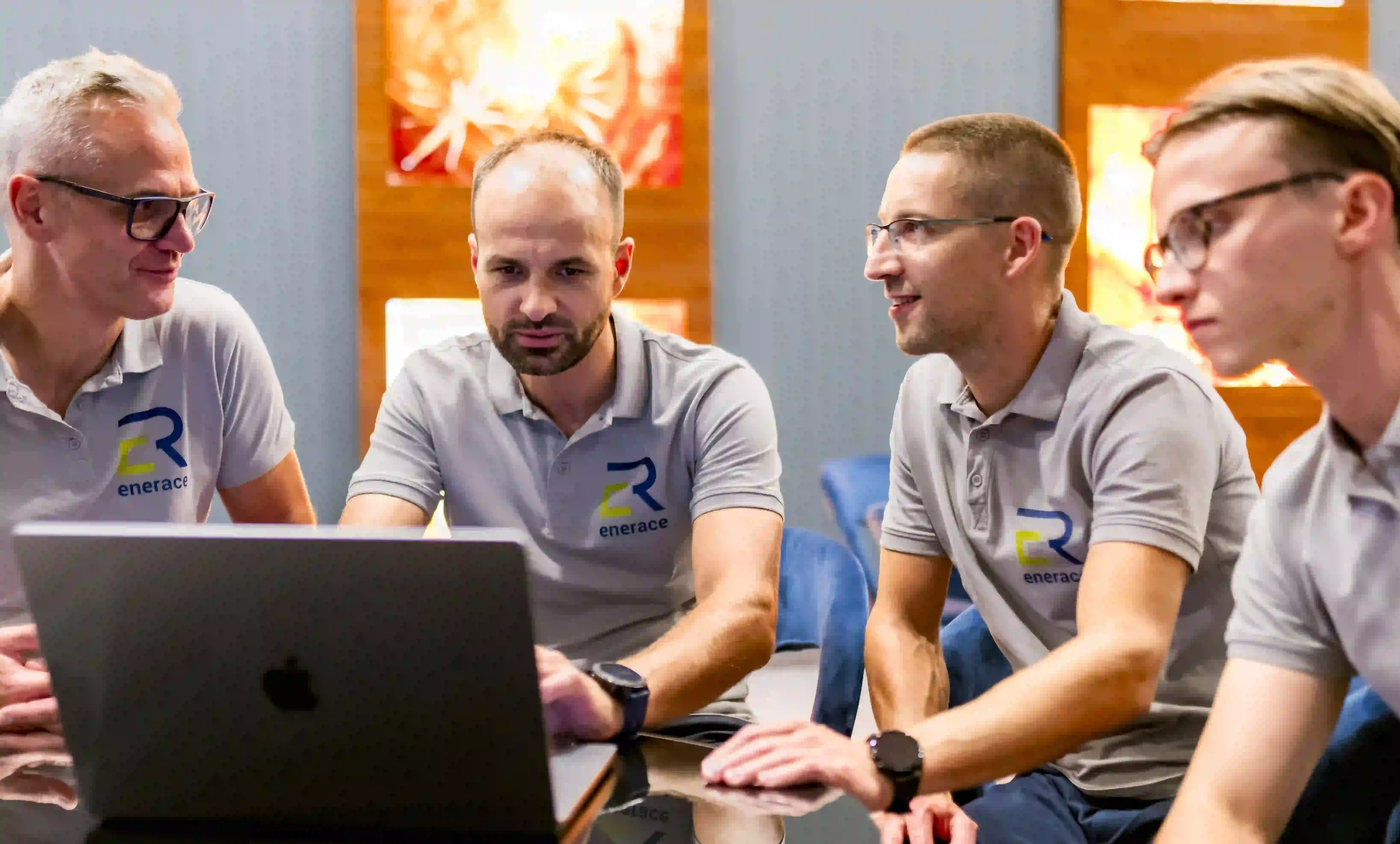 a group of men sitting at a table looking at a laptop